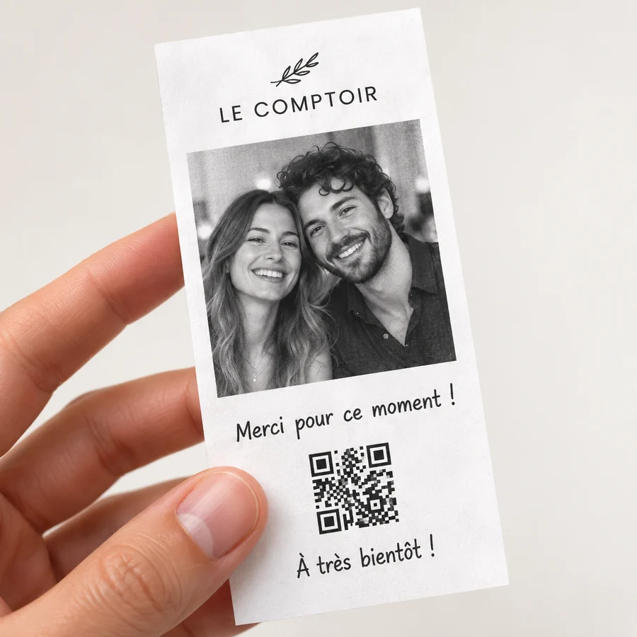 Des mains tiennent un ticket photo souvenir imprimé au restaurant